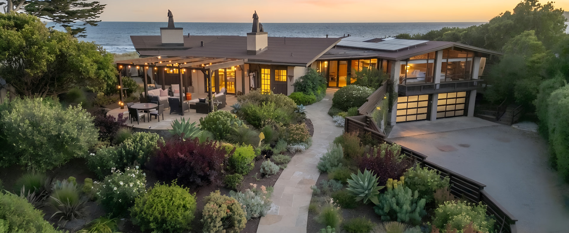 Coastal home with landscaped hardscape and outdoor living space at sunset