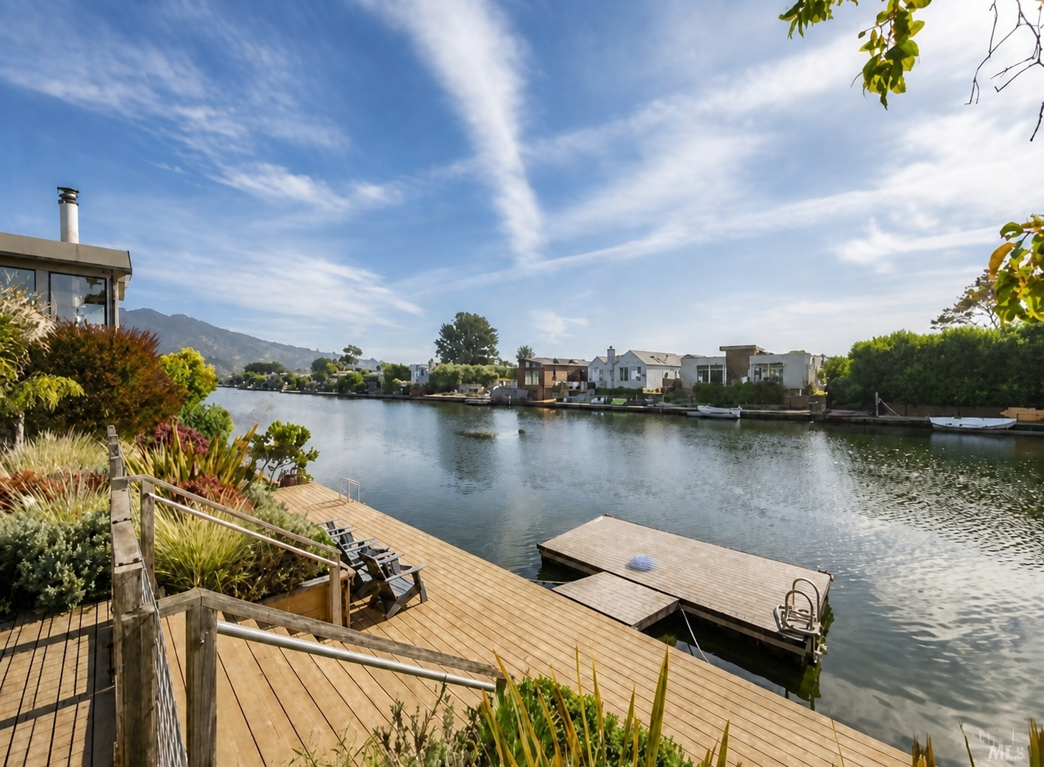 Lagoon-side wood deck with built-in planting beds, cable railing, and a floating dock